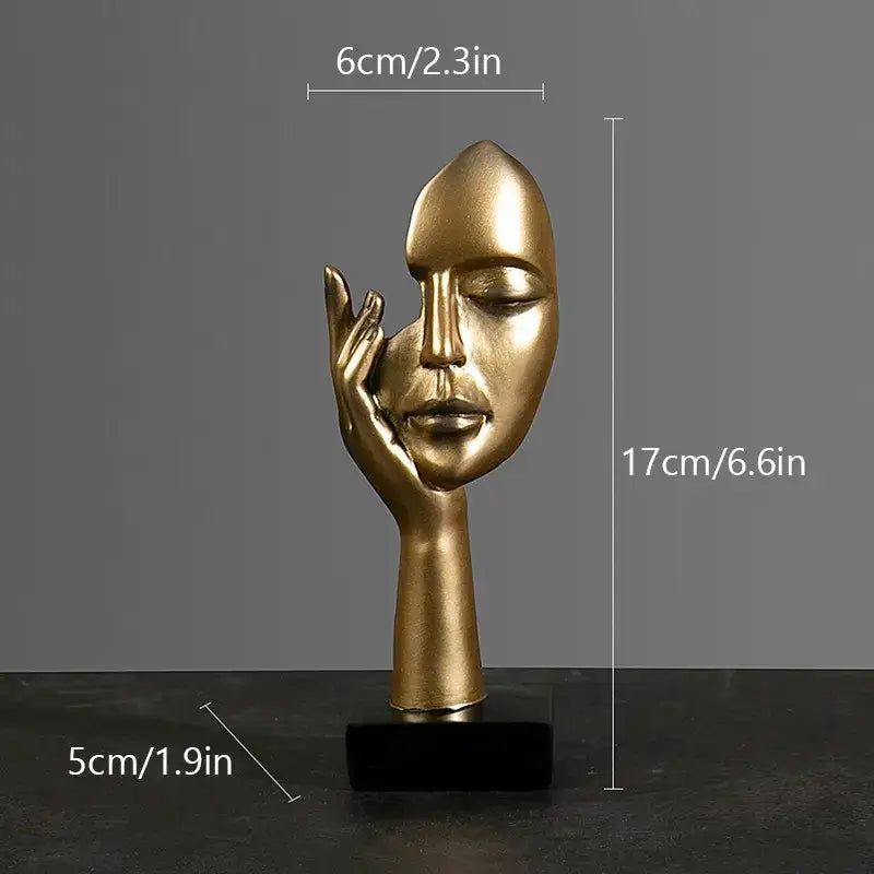Golden metallic sculpture of a face with closed eyes and hand on cheek on black base by decorbites abstract figurines
