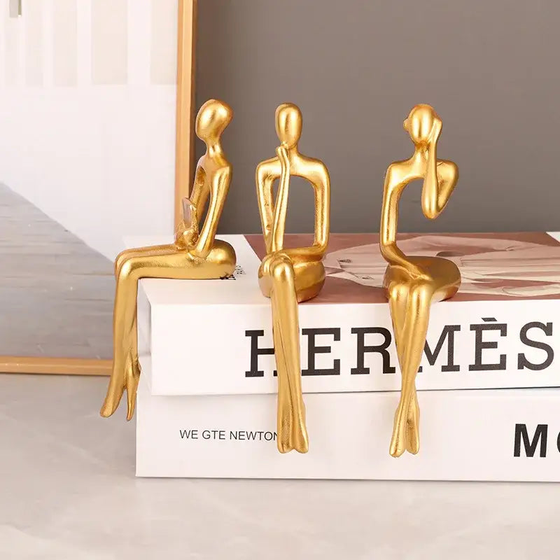 Three golden minimalist decorbites abstract figurines set of 3 on books modern art sculpture for home and office