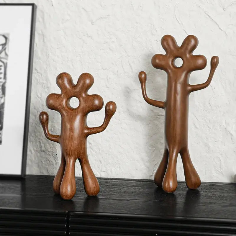 Two brown wooden decorbites abstract flower man figurines with rounded shapes and central head holes for home decor