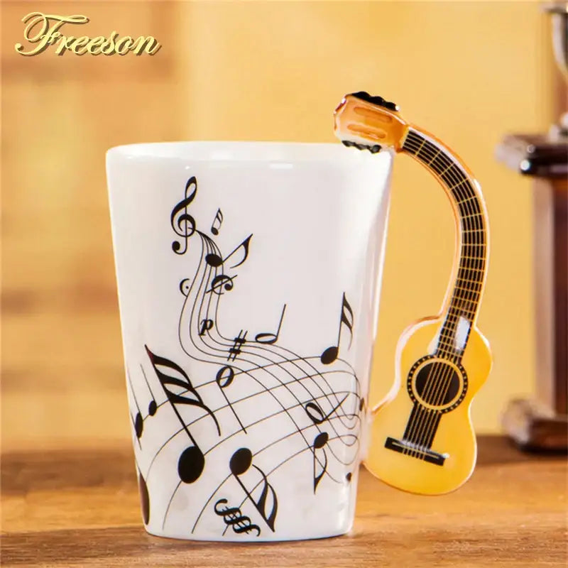 White ceramic acoustic guitar mug with black musical notes and yellow guitar-shaped handle branded freeson
