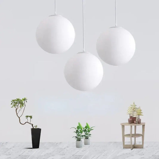 Three minimalist white acrylic ball pendant lights hang from the ceiling in a modern nordic living room setting
