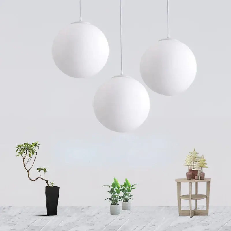 Three minimalist white acrylic ball pendant lights hang from the ceiling in a modern nordic living room setting