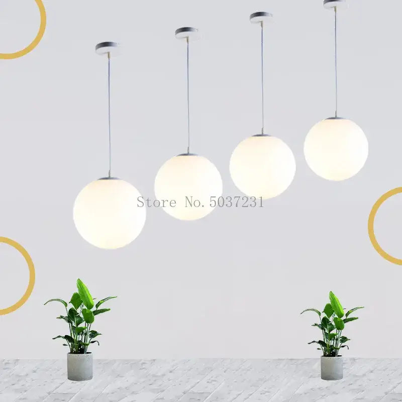 Four modern acrylic ball pendant lights with frosted white glass shades and metallic fixtures for living room decor