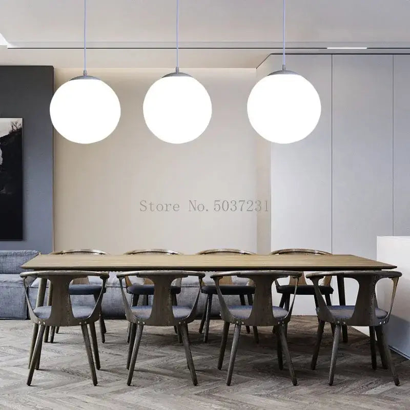 Three white acrylic ball pendant lights hang above a dining table in a modern nordic living room setting