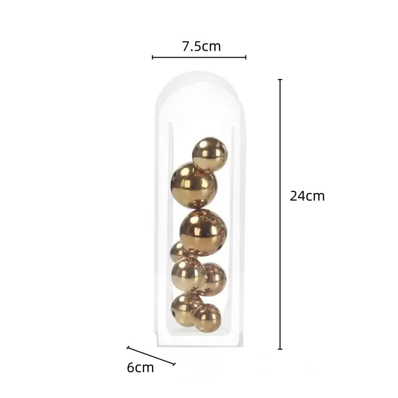 A clear plastic acrylic ball vase containing shiny gold metallic spheres in varying sizes for vase stack decor
