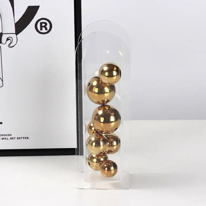 A clear acrylic ball vase stack with polished gold-colored metallic spheres for home decoration by decorbites