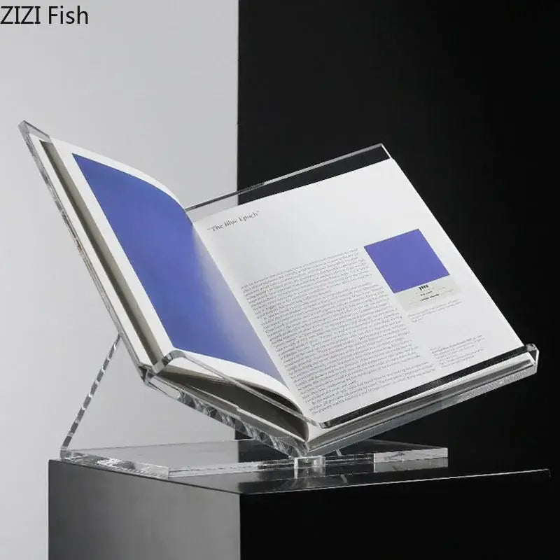 Clear acrylic bookshelf with marble base holding an open book with blue pages for modern home decor organization