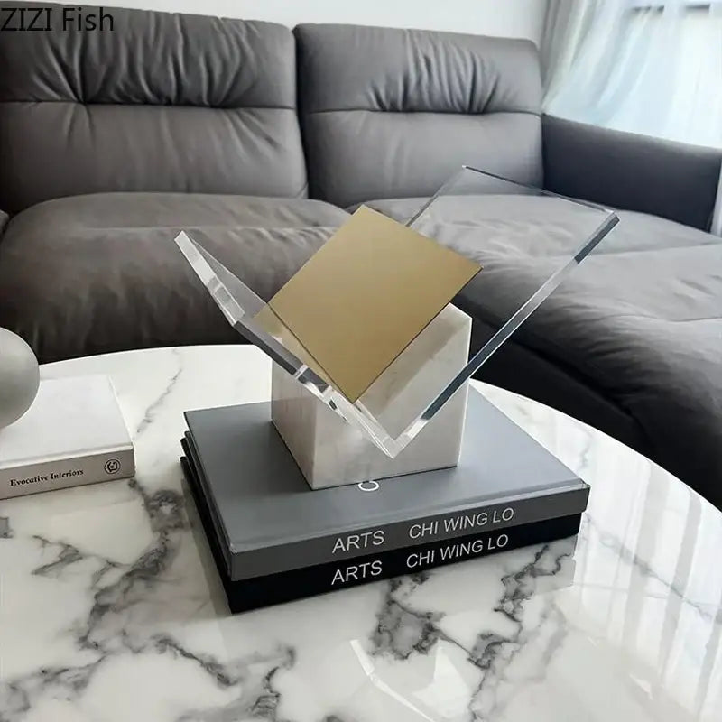 Modern acrylic bookshelf with clear geometric arms and gold-finished plate on marble base for home decor organization