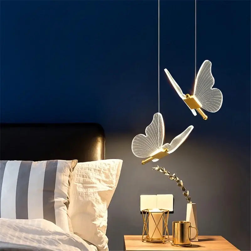 Two elegant decorbites acrylic butterfly led pendant lights with gold-toned metallic bodies hanging from ceiling