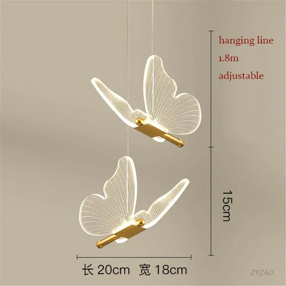 Two elegant translucent white acrylic butterfly led pendant lights with gold metallic bases hang from adjustable cords