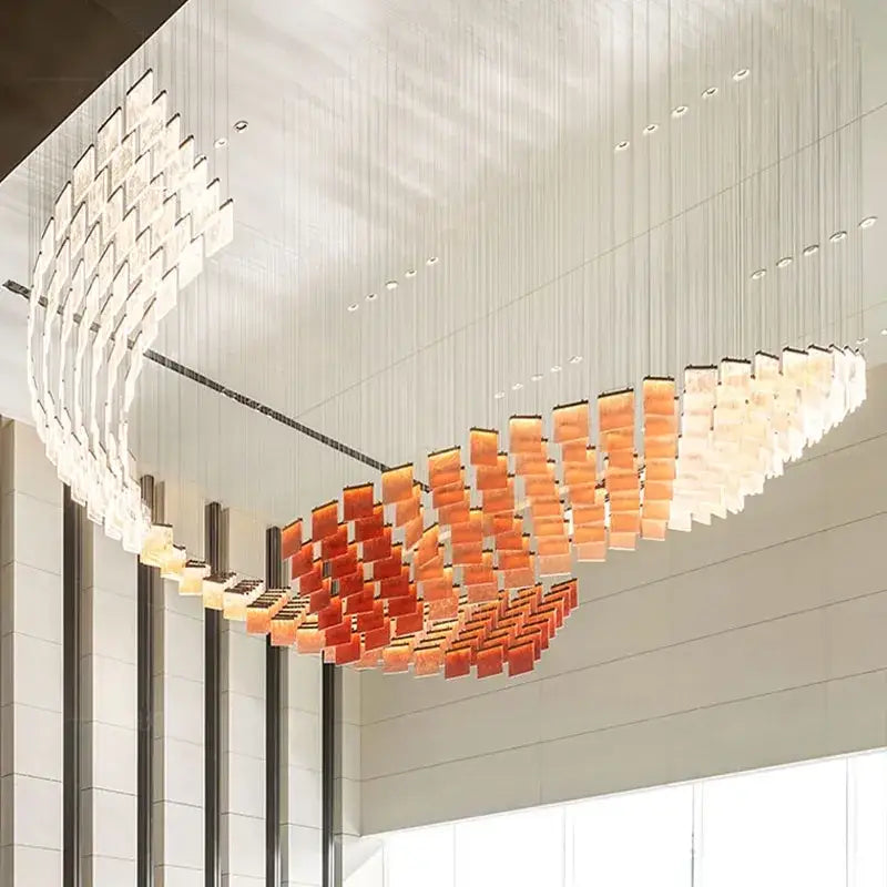 A modern curved acrylic chandelier lights with translucent glass panels in amber to white gradient for home lighting