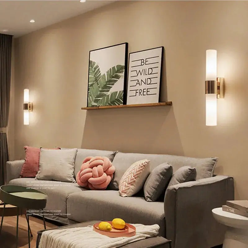 Modern gold-toned wall lamp featuring an acrylic cylinder wall design with a frosted glass shade for indoor lighting