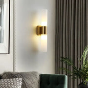 Modern gold-toned decorbites™ acrylic cylinder wall lamp with frosted glass diffuser emitting warm light for bedroom and living room