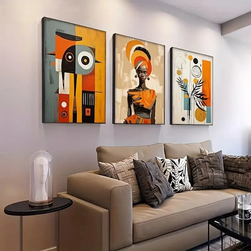 Three-piece DecorBites™ African abstract wall art set features bold orange, black, and gray geometric designs above a beige sofa