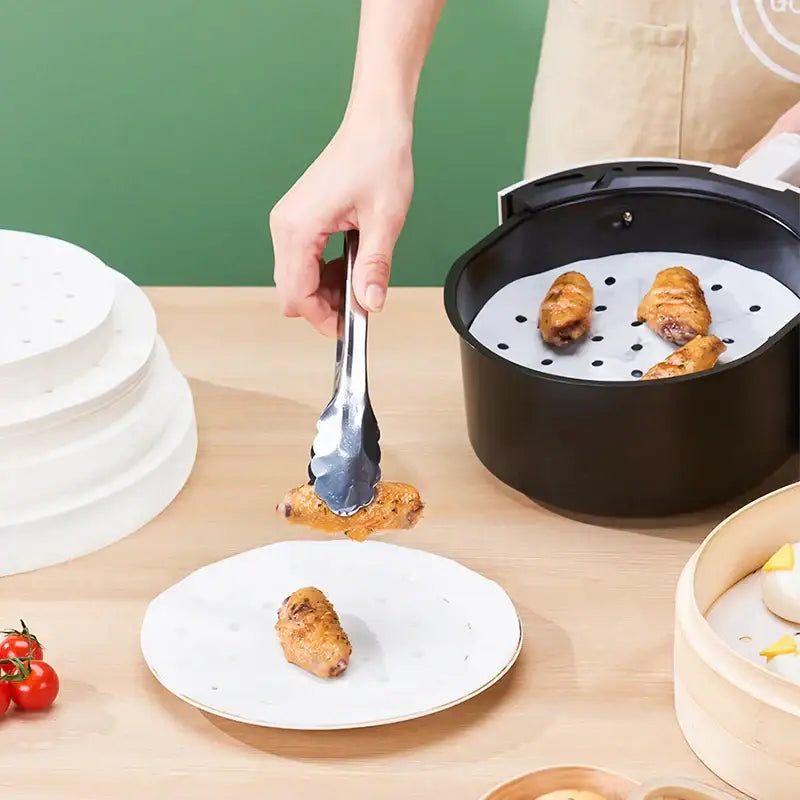 Golden crispy chicken wings lifted with metal tongs from an air fryer basket using decorbites™ air fryer steamer papers