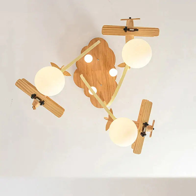 Wooden airplane chandelier light with three frosted glass bulbs and cloud-shaped base for nursery ceiling decor
