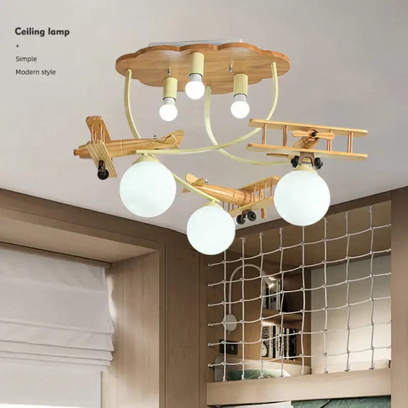 Wooden airplane chandelier light with three frosted globe shades and cloud-shaped base for nursery ceiling lighting