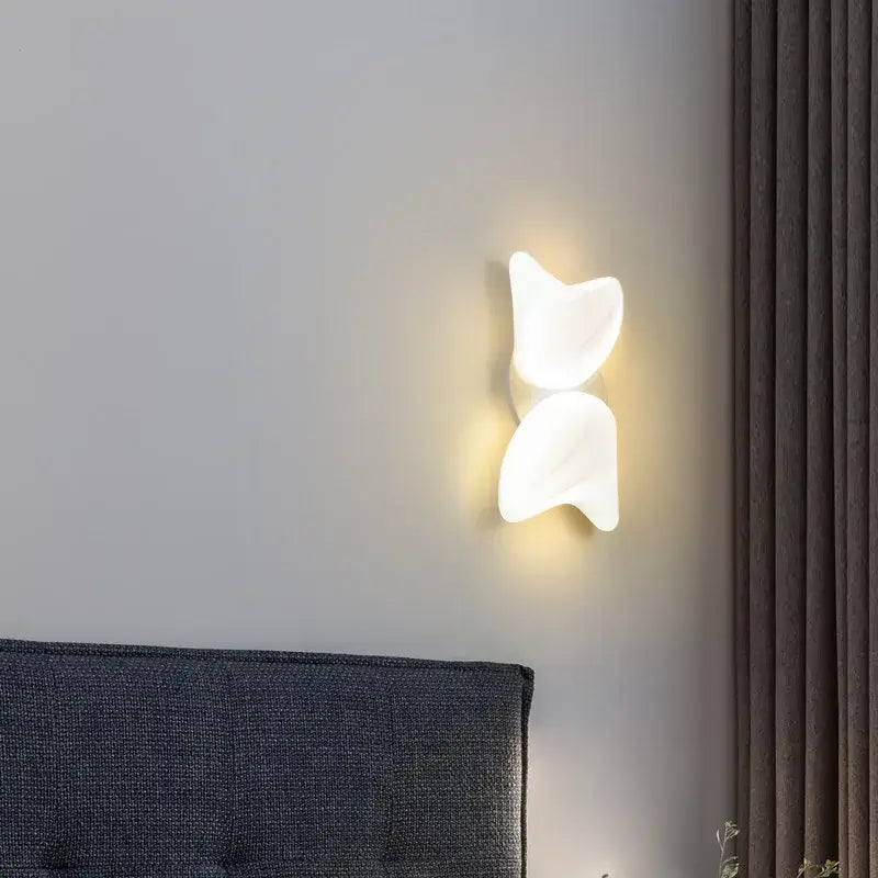 White minimalist wall sconce with smooth sculpted design complementing aisal flower ceiling chandelier decorbites modern home