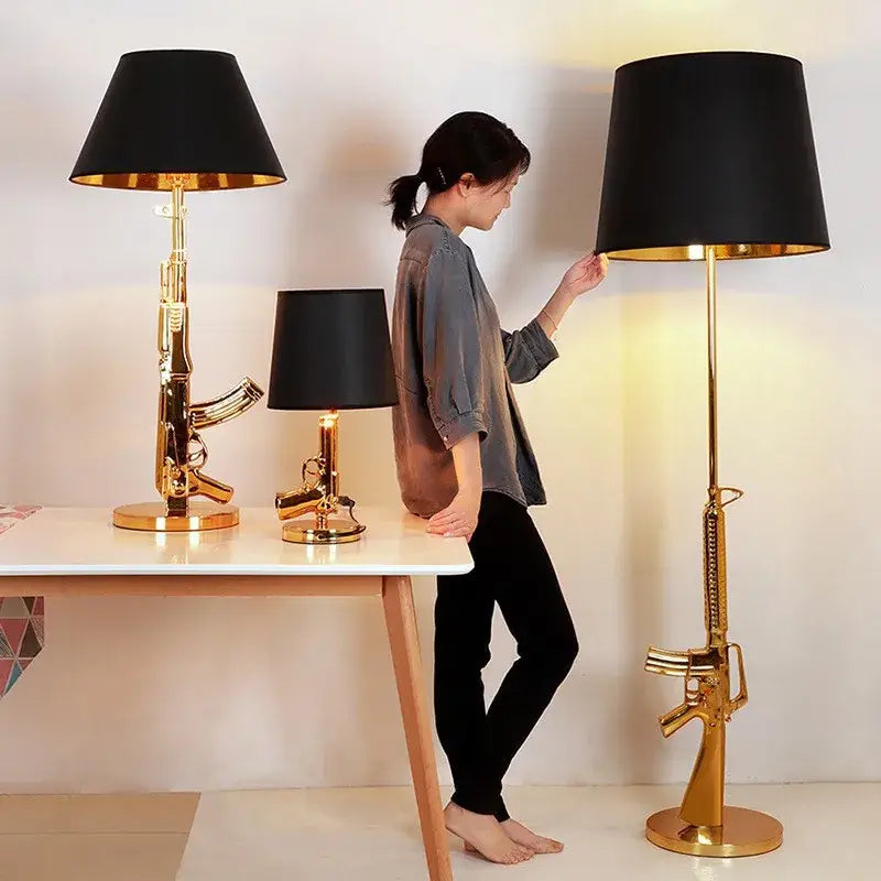 Gold-colored ak47 guns floor lamp with black fabric shade and golden metal electroplated finish by DecorBites