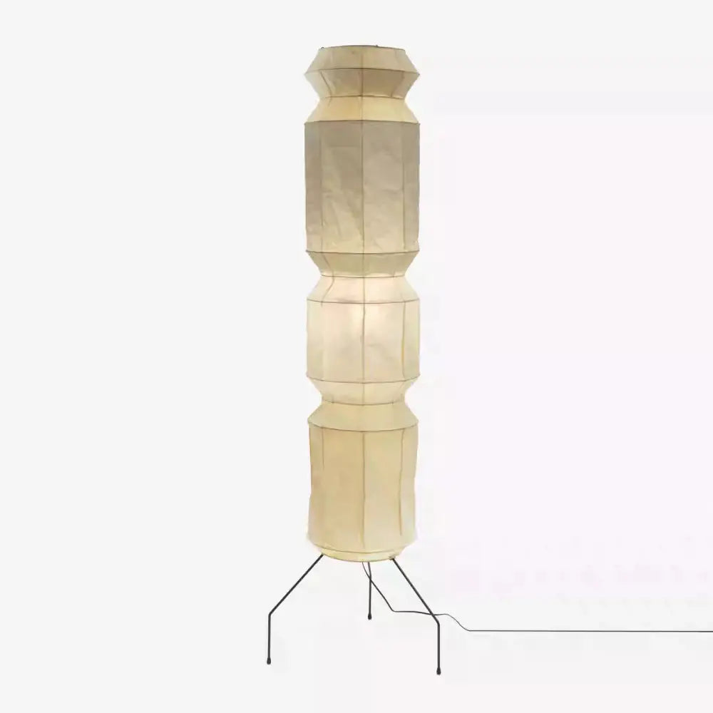 Cream-colored akari noguchi floor lamp with geometric rice paper shade and black metal tripod base for living room decor