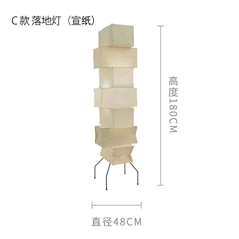 A tall cream-colored akari noguchi rice paper floor lamp with stacked rectangular sections and black metal base