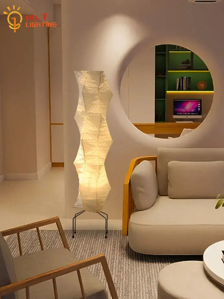 A tall cream-colored akari noguchi rice paper floor lamp with sculptural pleated design and black metal stand for living room decor