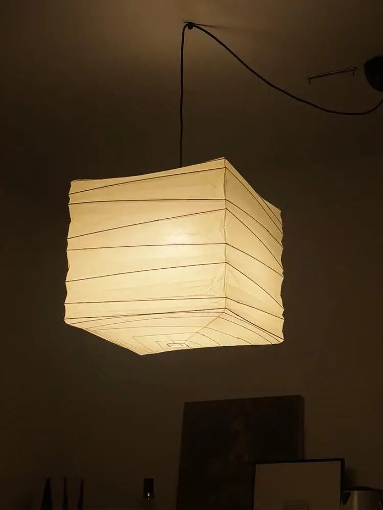 Warmly glowing DecorBites™ Akari Noguchi rice paper pendant light hanging from ceiling for bedroom or living room
