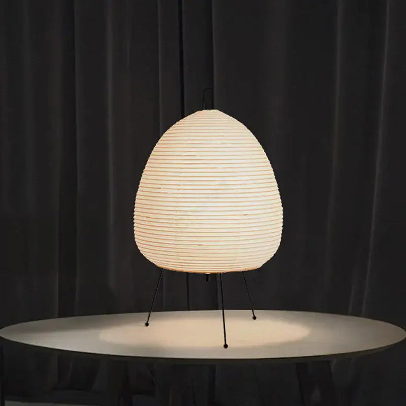 Cream-colored ribbed paper akari noguchi table lamp with sleek black metal tripod base for home and bar décor
