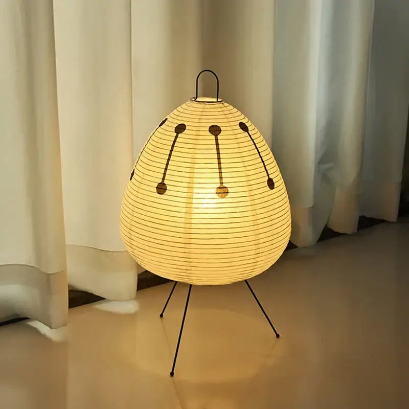 Warmly glowing decorbites akari noguchi table lamp with rice paper shade black metal frame and tripod base