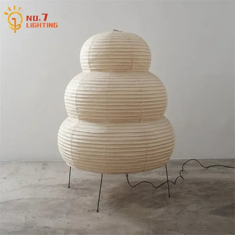 Cream-colored akari noguchi table lamp with tiered rice paper shade and slender metal legs for elegant lighting