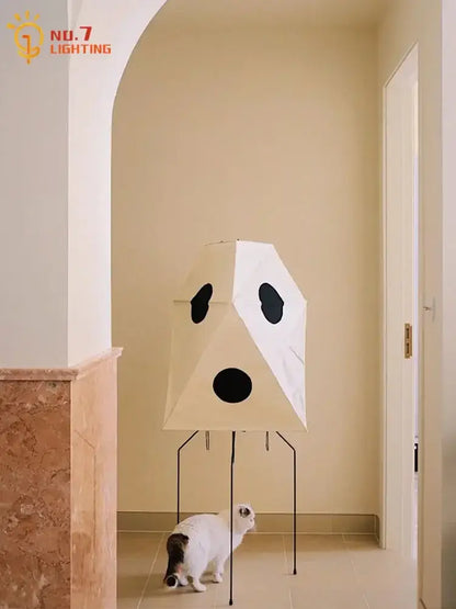 Cream-colored akari rice paper floor light with geometric design and black circular accents on thin metal legs