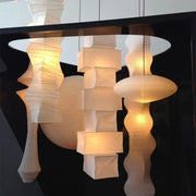A collection of illuminated white akari rice paper pendant lamps with geometric and organic shapes for living spaces