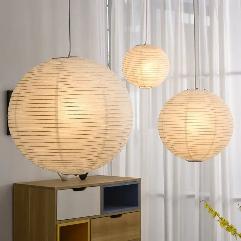Three warm glowing akari rice paper pendant lights with vertical ribbed texture for home décor by decorbites