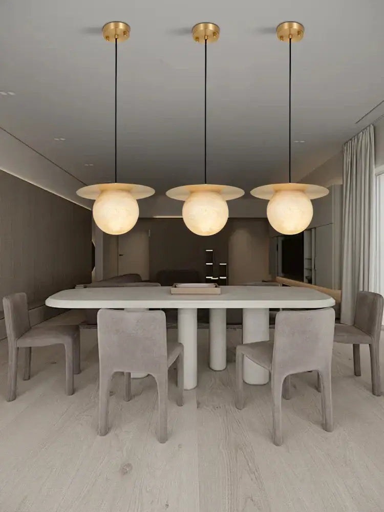 Three modern alabaster marble pendant lights with gold fixtures and frosted globes for luxury dining room décor