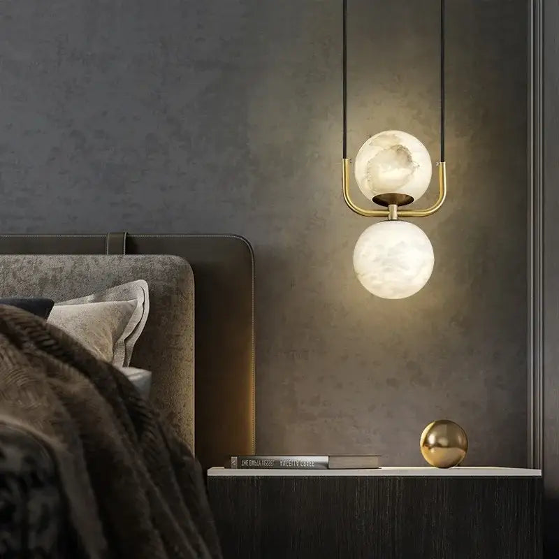 Modern pendant lights featuring two spherical alabaster marble pendant shades with brass hardware for luxury décor