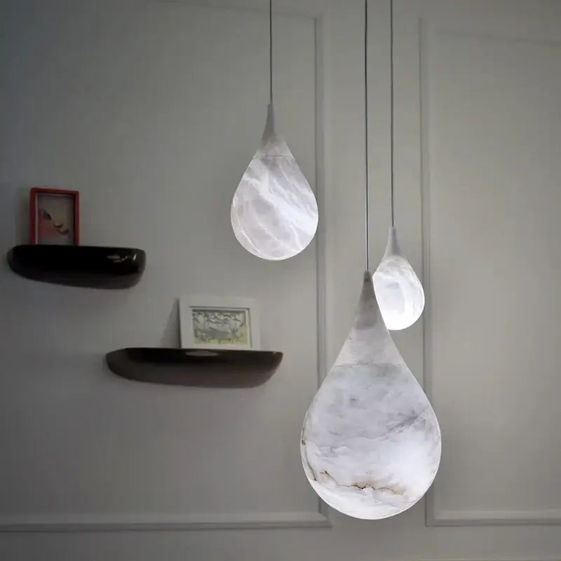 Three alabaster marble pendant lights with white marble finish and gray veining for luxury dining room décor