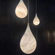 Three alabaster pendant lights with a swirling white and beige marble finish by decorbites for living room lighting
