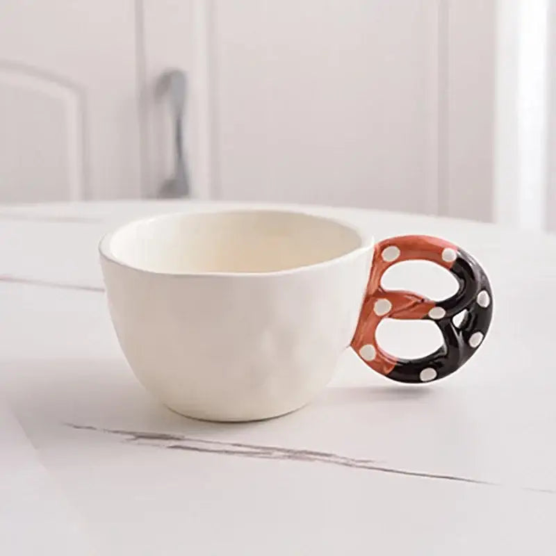 White ceramic alkali water biscuit mug with pretzel handle and black orange polka dot design for tea and coffee use