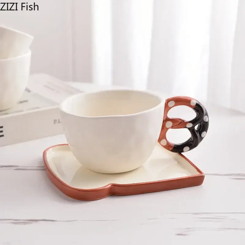 White ceramic alkali water biscuit mug set with black and orange pretzel handle and matching rectangular saucer