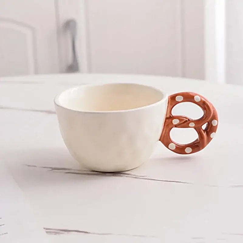 Cream-colored ceramic water biscuit mug with pretzel-shaped handle in brown glaze and white polka dots from decorbites alkali water biscuit mug set
