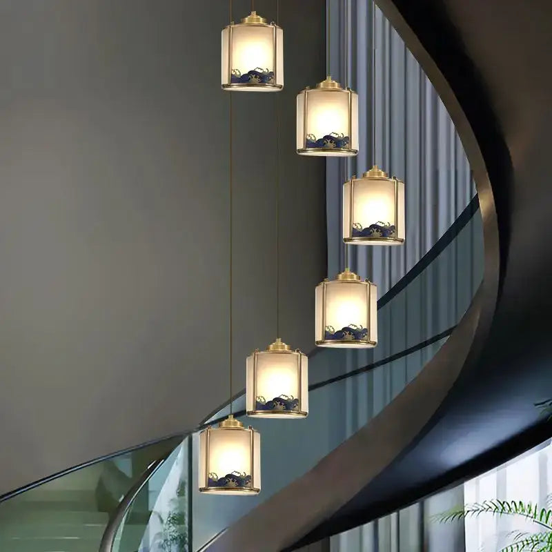 Five warm-lit brass pendant lights with translucent shades in a cascading copper entrance rotating staircase light design