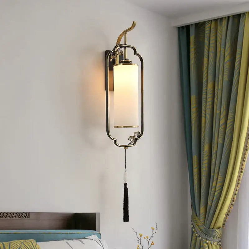 Brass-framed copper wall lamp with frosted glass shade and ornate tassel for living room or bedside light
