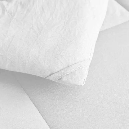 White pillow with textured crinkled fabric and stitched edges on a soft breathable brushed duvet quilt by decorbites