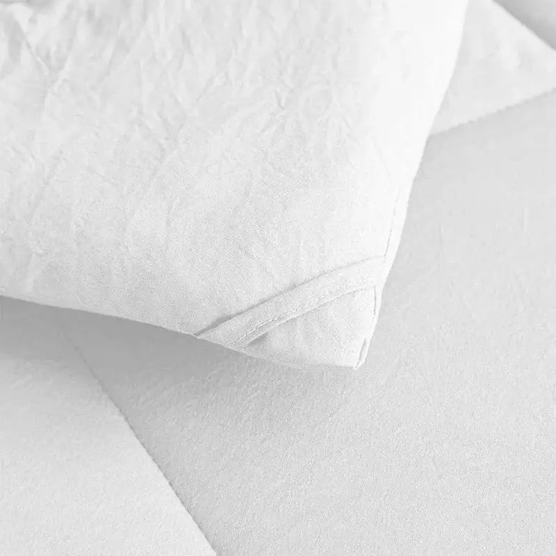 White pillow with textured crinkled fabric and stitched edges on a soft breathable brushed duvet quilt by decorbites