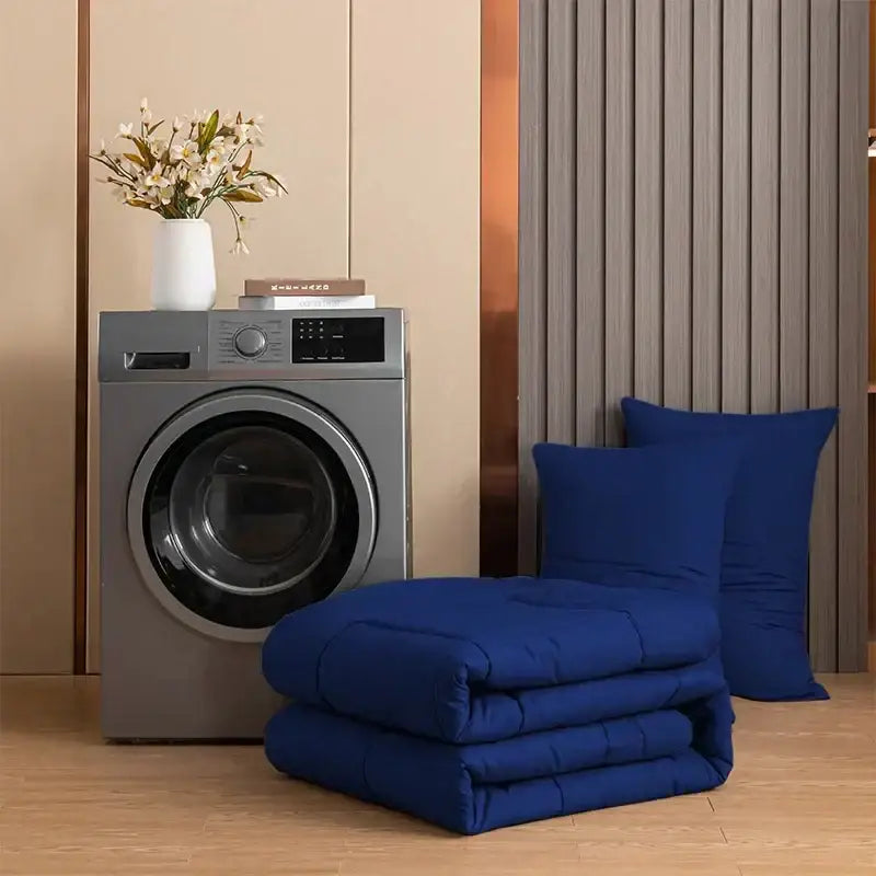 A plush deep blue decorbites™ quilted duvet set neatly folded beside a modern silver front-loading washing machine