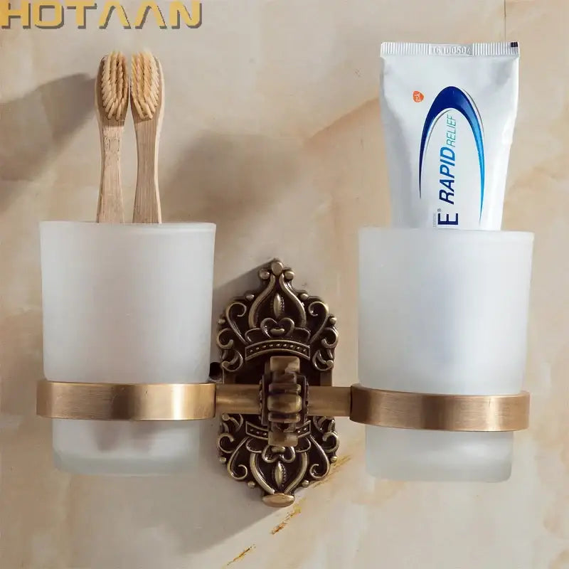 Antique brass-finished aluminium double tumbler holder with frosted glass cups and ornate decorative center for bathroom