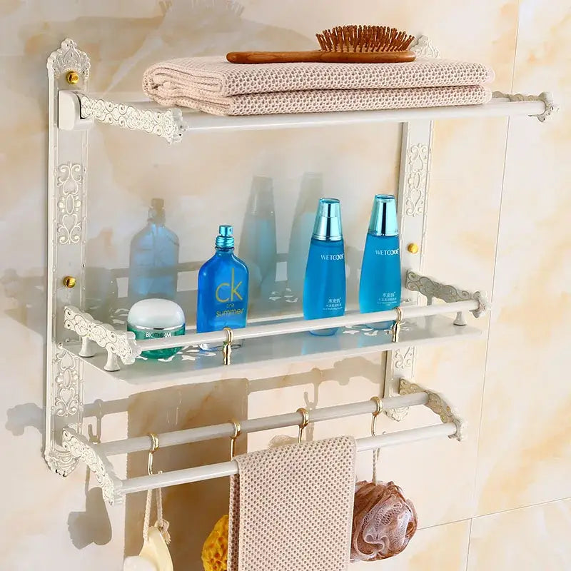 White ornate aluminum bath hardware set shelf with glass panels and metal hooks holding toiletries and towels