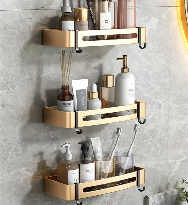 Gold-colored three-tiered aluminum bathroom corner shelf with sleek metallic finish and black hooks for wall-mounted storage