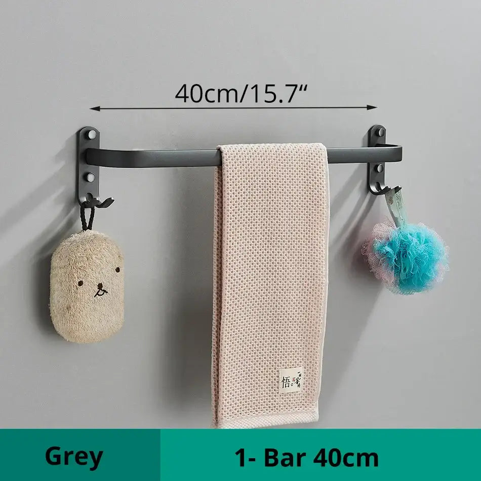 Grey aluminum bathroom towel rack with two hooks holding beige textured towel and decorative bath accessories