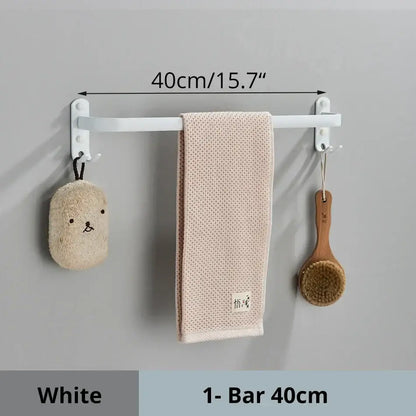 Decorbites aluminum bathroom towel rack in white holding a beige towel and two hanging bath accessories
